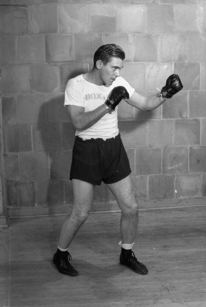 One of a group of twenty individual poses of boxers participating in the annual "Tournament of Contenders" which is open to all civilian and naval trainee students on the University of Wisconsin campus.  Included are: Dave Anderson, Nick Collias, Hank Coppolillo, Dave Dahl, Dick Gibson, Gene Johnson, Bob Leary, Bill Neary, Eddie Ossowski, Vito Parisi, Dave Reiels, Hugh Rubenstein, Joel Stone, Harold Sullivan, Bill Walsh, and Jack Zylka.