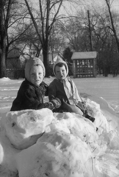 Winter scene with Anthony and Ritchie Purnell, children of Mr. and Mrs. William Purnell, 112 Kensington Drive, sitting on their snow fort.