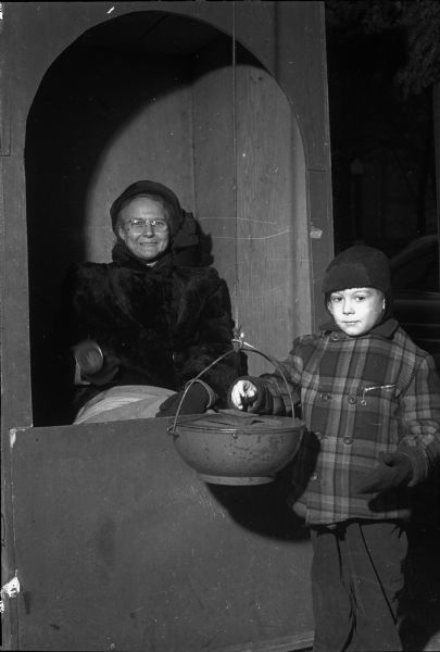 Mrs. Virginia McFadden, a worker at a Salvation Army kettle, receiving a contribution from Roger Helgesen, son of Floyd and Marian Helgesen, Milton.