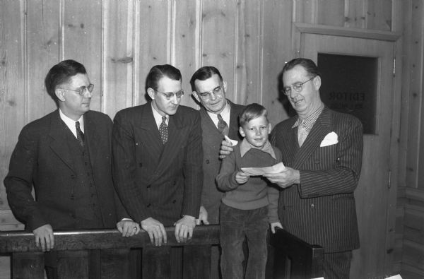 Left to right: Rufus Wells, associated with Roundy's Fun Fund; Dr. L.E. Holmgren, president of the Dane County unit of the WAD (Wisconsin Association for the Disabled); Phil J. Krsh, executive secretary of the WAD; Owen Watson, son of Mr. & Mrs. Charles H. Watson, severely burned last Christmas when his cowboy chaps caught fire, and Roundy Coughlin.