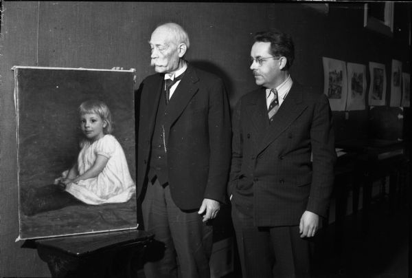 Julius Rehder, artist (1861-1955) with his son, University of Wisconsin-Madison Professor Helmut Rehder, looking at an oil painting done by the father when the boy was at a young age. The art exhibit was shown at the State Historical Society Museum.