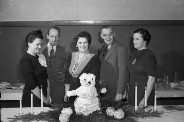 Nakoma Welfare League's traditional Twelfth Night Party at Nakoma School. Admiring the snowman table decoration are Mr. & Mrs. William F. (Marguerite) Grimmer, left; Mrs. Charles B. (Marianna) Stumpf, secretary of the league; Professor John A. James; and Mrs. Gerald E. (Josephine) Annin, treasurer of the league.