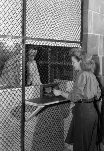 Lorraine Gray collecting her pay in cash at the paymaster's office at the RMR (Ruben-Mallory-Ray-O-Vac) plant, a division of Ray-O-Vac located in the 1400 block of East Washington Avenue. The plant manufactured batteries for walkie-talkies used for the military during World War II.