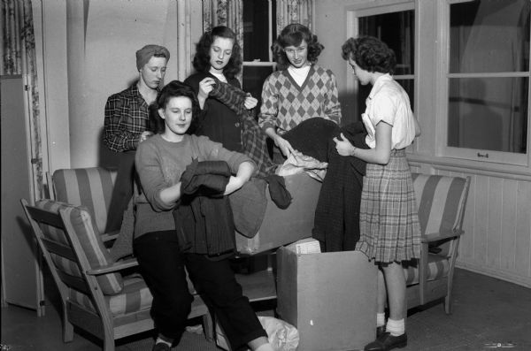 Five Girl Reserves (?) shown with items of clothing collected for the war effort.