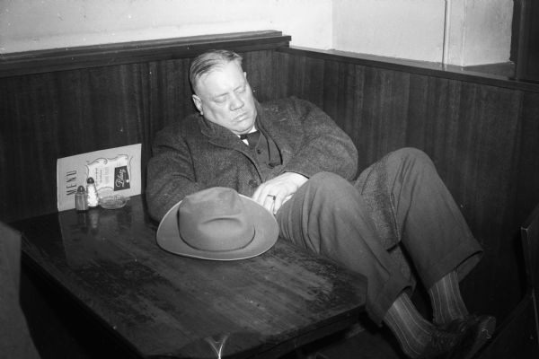 A man, possibly Ray Gryphan, clerk at Loraine Hotel, seen sleeping in restaurant booth.