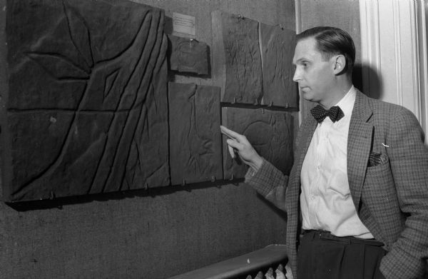 Prof. H. Scudder Mekeel looking at recreated petroglyphs based upon carvings found on the walls of an Indian rock shelter now called Gullickson's Glen near Disco in Jackson County, Wisconsin. This was part of a display in the State Historical Society Museum.