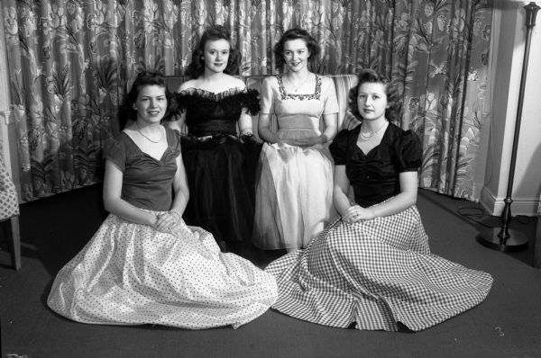 The court of honor for the queen of the 26th annual Little International Livestock and Horse Show, held in the Stock Pavilion on the Agricultural campus of the University of Wisconsin-Madison. The event is sponsored by the Saddle and Sirloin Club. Pictured left to right: Jean Hird, Lillian Anderegg, Delia Rossini, and Myrtle Baumann, Home Economics students at the university.