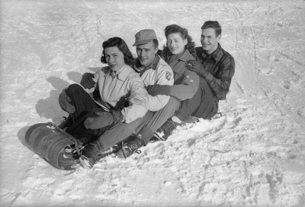 Four University of Wisconsin students participate in the the 13th Annual Winter Carnival held at the University of Wisconsin campus. Pictured sitting on a toboggan are: Nancy Lou Whitely, Fond du Lac, chairman of ice sculpturing; Walter Evanson, Oshkosh, chairman of the iceboat regatta; Millicent Stein, New Rochelle, New York, head of promotions; and Jack Bunten, Antigo, publicity chairman.
