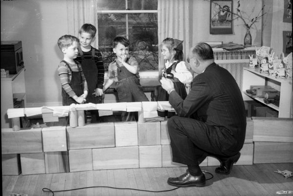 Man talking with four children at the University of Wisconsin-Madison, Home Economics School, Child Development nursery school on Linden Drive.