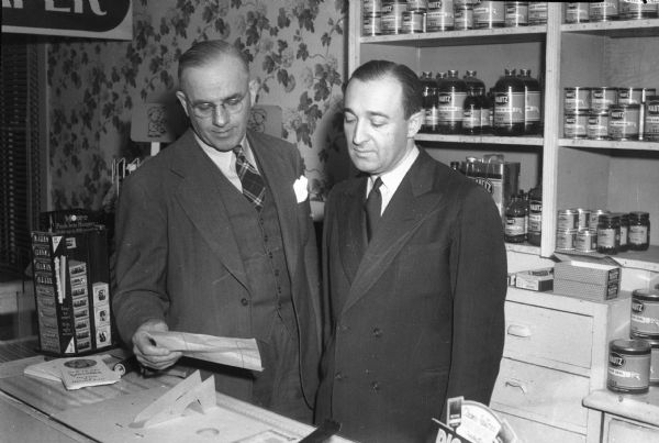 Portrait of J.H. Svendsen (left), owner of Svendsen's Painting and Decorating Firm at 118 State Street, and Joe Borecek, retail store manager. The store was formerly operated under the name "Mautz Brothers."