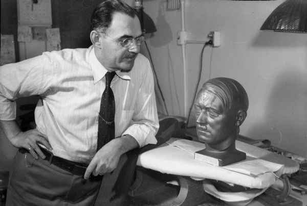 K. Peter Yust, 205 Division Street, a tailor at C.W. Andres Company, looking at a bust of Adolph Hitler.