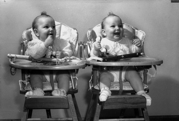 Donald R. and Ronald R. Jacobson, identical twins of Irving and Minnie Jacobson, sitting in highchairs. The Jacobsons were owners of the Norris Court and Flom Apartments.