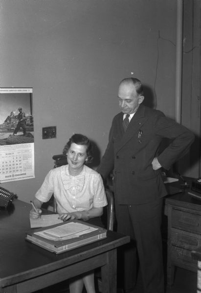 Joe and Jerry Ness in the office of the Ness Roofing and Supply Co., 2632-34 Milwaukee Street. Mrs. Ness has been associated as a bookkeeper in her husband's business since it was organized in April, 1941.