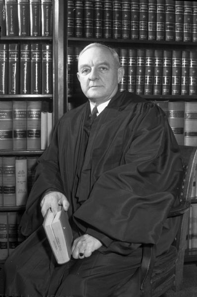 Judge Elmer E. Barlow, in his robes, sitting in his office, as a member of the Wisconsin Supreme Court.
