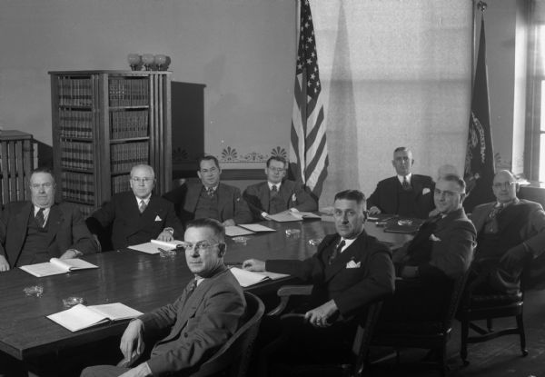 Group portrait of Wisconsin Assembly Veterans and Military Affairs Committee seated around a table at the Wisconsin State Capitol.