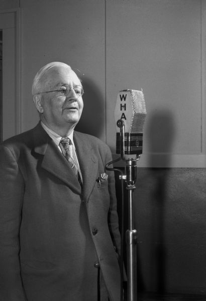 Prof. Edgar B. Gordon (Emeritus) at WHA radio microphone instructing Wisconsin children in vocal music at their schools, part of the "Journeys in Music Land" weekly broadcast on WHA's Wisconsin School of the Air.