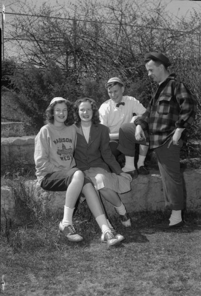 Four West High School students in their casual attire, blue jeans, "jeep" and pork pie hats, sports jackets, and bobby socks. Left to right: Phyllis Bakken, Elizabeth Crownhart, Jack Clemens, and Tom Reese.