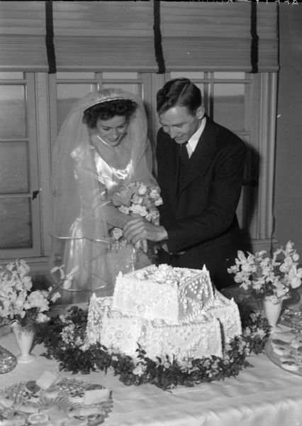 Dr. Forde A. McIver and Ruth Raymond Huegel McIver are cutting their wedding cake. He is the son of E. Roderick McIver, Darlington, S.C., and she is the daughter of Dr. and Mrs. Raymond W. (Freda C.) Huegel, 1829 Van Hise Avenue. The First Congregational Church was the scene of the wedding.