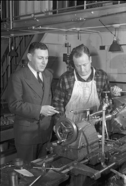 Clarence L. Greiber, Director of the Wisconsin State Board of Vocational and Adult Education, with Lester Morrisey, a discharged World War II veteran, shown in the Madison Vocational School shops. Greiber is involved in preparing for the post-war period and the influx of veterans into the adult vocational system.