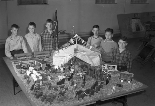 Six scouts, all members of Den 1, Pack 309, of the Lapham School Cub Scouts, with a toy circus displayed in the window of the F.W. Karstens store, 24 North Carroll Street. The miniature circus was designed and made by the six boys along with three other members of the den who are not pictured.  From left to right are: Charles Johnson, Leslie Crapp, David Brodhead, Armin Farness, Gary Melcher, and Lamar Blankenship.