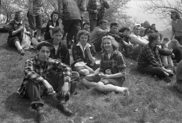 University of Wisconsin-Madison annual student work day at Picnic Point. Shown are four students at lunch break. Left to right: Dominic Cefalu, John E. Hade, Jeanne Wheeler and Alice Hafner. Other people are sitting in the background.