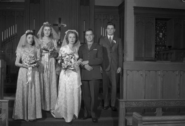 Wedding photograph of bride Elaine I. Luloff, groom Lieutenant Frederick J. Goff, Jr., maid of honor Mary Jo Kalland, bridesmaid Lucy Abbott and best man Richard N. Goff in front of the altar at Bethel Lutheran Church.