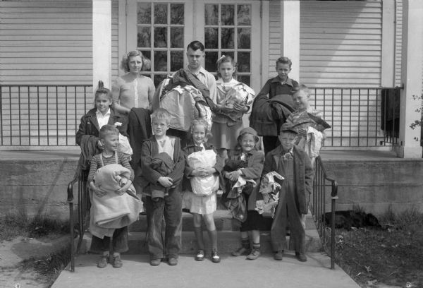 Eleven students from Highlands-Mendota holding clothes collected for the Madison and Dane County clothing drive. Pictured are room captains, first row left to right: Ronnie Merrick, Donald West, Kitty Dubielzig, Carol Kaeser, Robert Pigorsch. Second row left to right: Nancy Thomsen, Jeanette Becker, Douglas Stone, Caroline Forsmo, Robert Rosa, and Bruce Johnson.