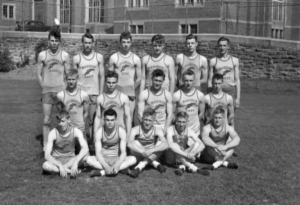 Group portrait of Madison East High School undefeated track team. Bottom row left to right: Bill Sullivan, Charles Fess, Charles Dorn, Roland Hanson, and Don Stevens. Middle row left to right: Al Larvick, Jerry Wrend, Duane Sydow, Lyle Levenich, and Don Erickson. Top row left to right: Harlan Huntley, Bill Lueptow, Ken Sachtjen, Howard Soderholm, Bruce Watson, and Dick Lampe.