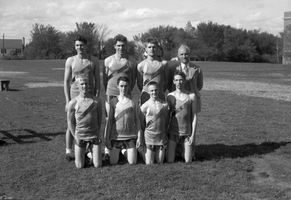 Group portrait of Madison West High School track team. Pictured in the bottom row, left to right: Tom Yorkson, Bill Weeks, Paul Toltzien, and Clyde Tarbutton. Back row left to right: Gil Coluccy, Bob Mansfield, Greg Blied, and coach Willis Jones.