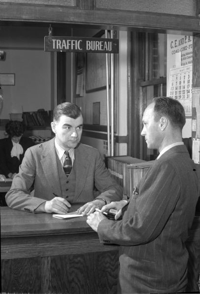 Police Captain, J. Homer Elder, new Chief of Traffic, talking with a citizen at the Traffic Bureau window.