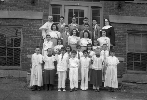 Group portrait of the eighth grade graduation class with priest, nun and altar boys in front of St. Joseph's Catholic School, 901 Bowen Court in the Greenbush neighborhood.