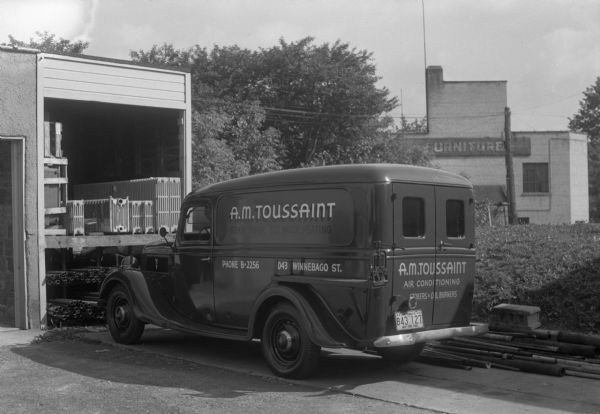 A.M. Toussaint Company's panel truck parked outside their office at 2043 Winnebago Street.
