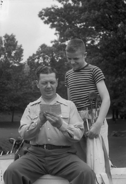 Lester and Robert Lee, 4229 Wanda Place, looking at golf score card.