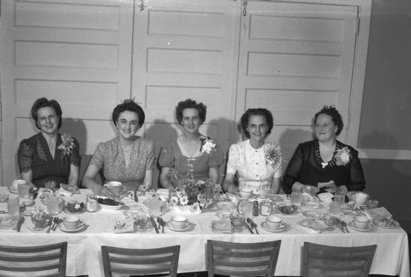 Group portrait of members of East Side Business Club at speaker's table at spring banquet. Seated left to right: Mrs. J.H. Stumpf (Mildred), 2147 Oakridge Avenue; Mrs. Ernest Anderson (Gertrude), 253 Kensington Drive; Mrs. Irving Goff (Ruby), 509 Maple Avenue; Mrs. Lorenz Leifer (Dorothea), 148 Rutledge Street, and Mrs. Russell Goodman (Edith), 1312 Williamson Street.