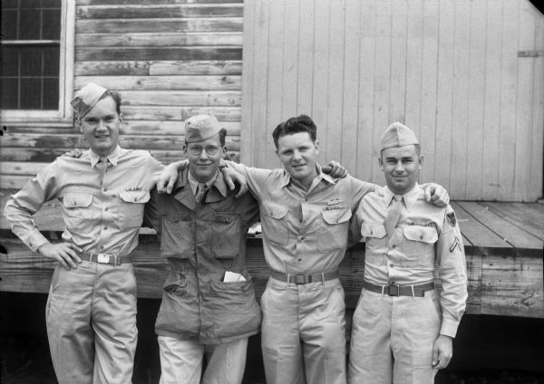 Group portrait of four Madison GIs (Blackhawks) who rode from Camp Grant, Rockford, Illinois, to their doorsteps in Madison in a <i>Wisconsin State Journal</i> car. Left to right: Pvt. Wilbur J. Hoxie, Pfc. Howard A. Endres, Pfc. William L. Clapp, and Pvt. Ervin M. Lichte.