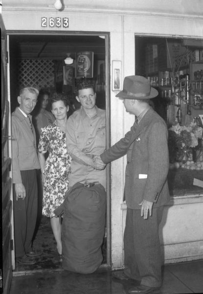 Pvt. William L. Clapp and his parents, David and Della Clapp, 2633 Milwaukee Street, in a doorway saying goodbye to Lawerence Fitzpatrick, <i>Wisconsin State Journal</i> city editor. Pvt. Clapp has just returned home from Camp Grant in Rockford, Illinois, in a <i>Wisconsin State Journal</i> car.