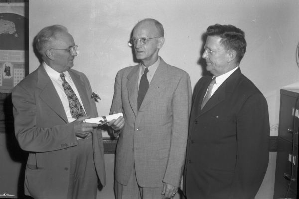 C.D. Lehman, superintendent of the State Public School, Sparta, receiving a certificate of service from Herman A. Kloppmann, board president, with A.W. Bayley, welfare department director, looking on. The school was for orphaned and neglected children. (The board called the Lehmans "a most unusual couple" whom hundreds of children will remember").