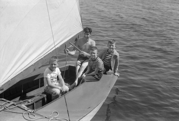 A counselor, Marty Steiner, is shown with three campers: Richard Pope, Michael Donagan and Robert Winslow, in a sailboat at YMCA Camp Wakanda on Lake Mendota.