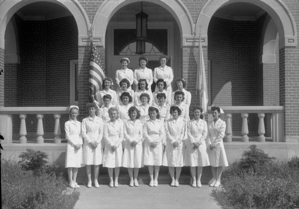 Group portrait of 21 nurses, standing on the steps in front of Alumni Hall, 1100 Delaphaine Court, at St. Mary's Hospital. They graduated from St. Mary's Hospital School of Nursing on June 24, 1945.