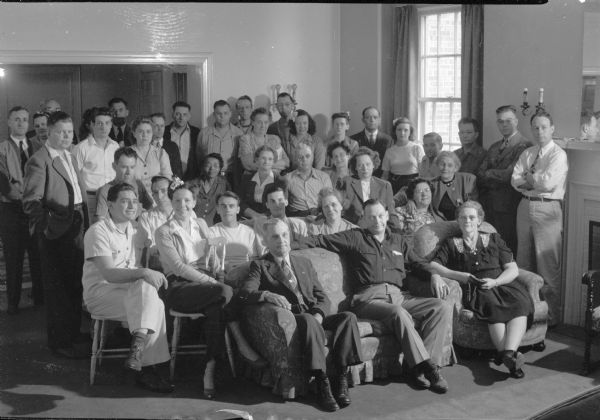 Group portrait of Summer Institute class. The Abraham Lincoln School for Social Science of Chicago, Illinois, sponsored a Summer Institute in Madison for several summers, including 1945.  The students who attended the two week sessions were mostly adult union workers and their families. They lived in rooming houses on Langdon Street and Lake Lawn Place, attended lectures and participated in recreational activities. The photographs show the teachers with groups of students, both indoors and out-of-doors, the students participating in recreational activities such as boating and badminton and the children with a day care worker. The School was run by former University of Wisconsin Associate Professor of Classics Alban D. Winspear. Their textbook was called "Why Work for Nothing" espousing Marx's theory of value. The school had a communist / leftist philosophy and was often confused with the University of Wisconsin's School for Workers.
