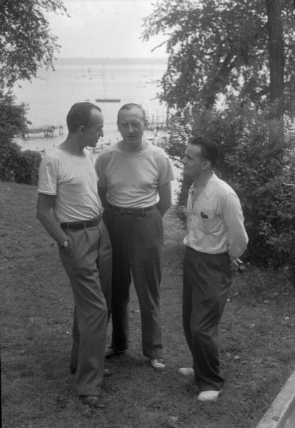 Three men standing out of doors, probably the Abraham Lincoln School, Summer Institute teachers: Philip S. Fonert, A.D. Winspear and Claude Williams. The Abraham Lincoln School for Social Science, Chicago, Illinois, sponsored a Summer Institute in Madison for several summers, including 1945. The students who attended the two week sessions were mostly adult union workers and their families. They lived in rooming houses on Langdon Street and Lake Lawn Place, attended lectures and participated in recreational activities. The photographs show the teachers with groups of students, both indoors and out-of-doors, the students participating in recreational activities such as boating and badminton and the children with a day care worker. The School was run by former University of Wisconsin Associate Professor of Classics Alban D. Winspear. Their textbook was called "Why Work for Nothing" espousing Marx's theory of value.  The school had a communist / leftist philosophy and was often confused with the University of Wisconsin's School for Workers.