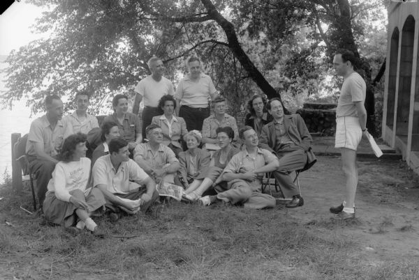 Group of students on the lawn listening to a teacher. The Abraham Lincoln School for Social Science, Chicago, Illinois, sponsored a Summer Institute in Madison for several summers, including 1945.  The students who attended the two week sessions were mostly adult union workers and their families. They lived in rooming houses on Langdon Street and Lake Lawn Place, attended lectures and participated in recreational activities. The photographs show the teachers with groups of students, both indoors and out-of-doors, the students participating in recreational activities such as boating and badminton and the children with a day care worker. The School was run by former University of Wisconsin Associate Professor of Classics Alban D. Winspear. Their textbook was called "Why Work for Nothing" espousing Marx's theory of value. The school had a communist / leftist philosophy and was often confused with the University of Wisconsin's School for Workers.