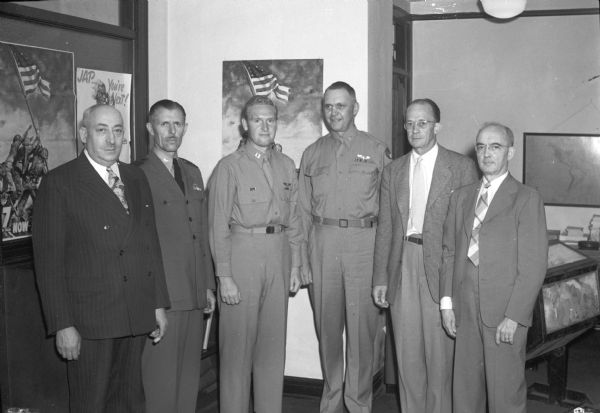 Judges for a War bond drawing. Pictured are: S.L. Goldstine, city chairman; Capt. L.K. Pollard, Commanding Officer of Naval School; Capt. Harold Helstrom; Col. W.T. Meyer, representing Brig. Gen. Meloy of Truax Field; Vern S. Bell, Dane County Chairman; W.T. Cullinan, in charge of presentation. The Seventh War Loan Drive was a success for Dane County in reaching the goal for sales.