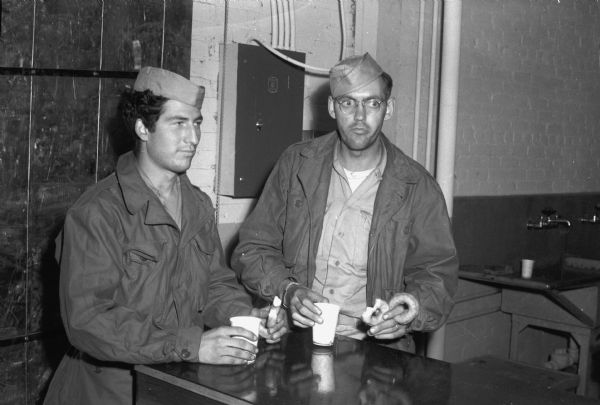 Corp. Anthony J. Tranpino, left, and Tech. 5th Grade Robert Wilson, right, having refreshments at Camp McCoy after arriving for a short furlough before re-deployment to the Pacific.
