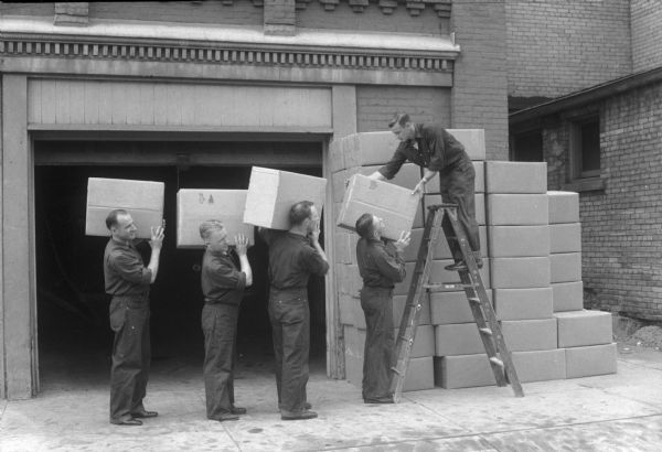 Madison fire fighters load Red Cross boxes to send overseas. Each box contained 36 knit bags made and filled by volunteers, each bag contained a pencil, stationary, cigarettes, playing cards, a novel, shoestrings, razor blades, candy, soap and sewing tools. Fire fighter helpers are: Charles Tomcany, Ralph McGraw, Edward Bokina, Edward Knope, and Marvin Kammer.
