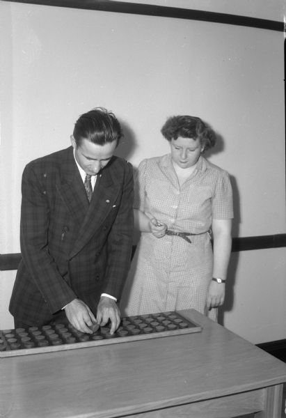 A woman timing a man performing a vocational test - possibly a World War II veteran.