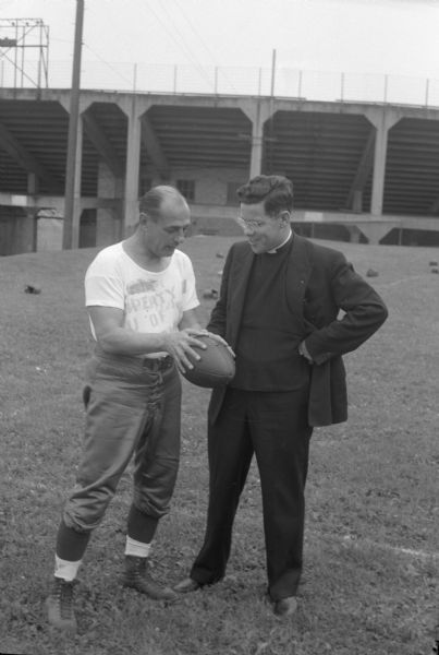 A priest with a coach holding a football.