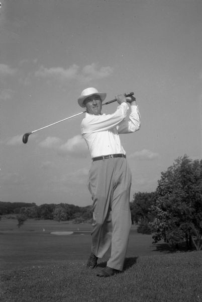 A man swinging a golf club on a golf course.