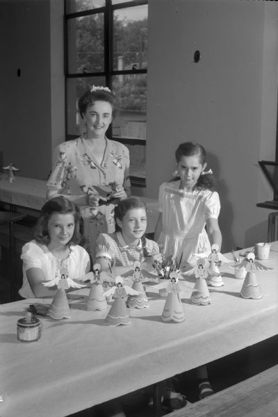 Members of the Junior Red Cross of Madison making Christmas cards, tray favors, Christmas tree ornaments, and recreation hall decorations for service units and hospitals overseas. Mrs. Ernest Anderson, director of the Junior Red Cross activities in Madison, is shown with three of her volunteer workers, from left to right: Maralyn Savage, Jane Botham, and Raelyn Stroud.