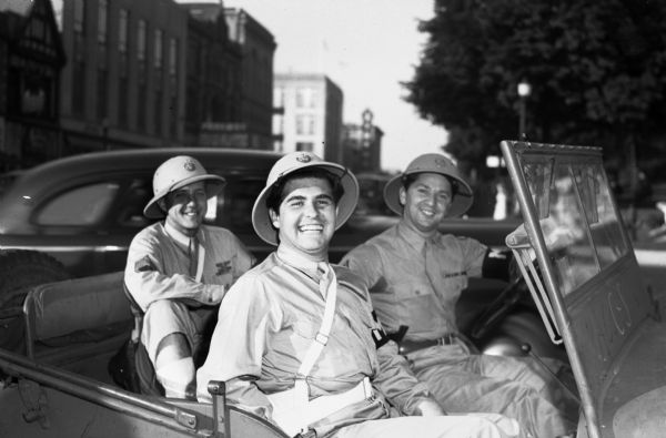 Pfc. Arthur Lovinger, passenger in the front seat; Staff Sgt. Robert Hanke, passenger in the back seat; and Staff Sgt. Louis Kaminsky, driving a car. They are celebrating V-J Day, August 15, the day on which the Allies announced the surrender of Japanese forces during World War II.